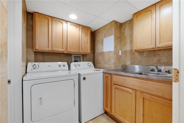 clothes washing area featuring cabinets, sink, washing machine and dryer, and light tile patterned floors