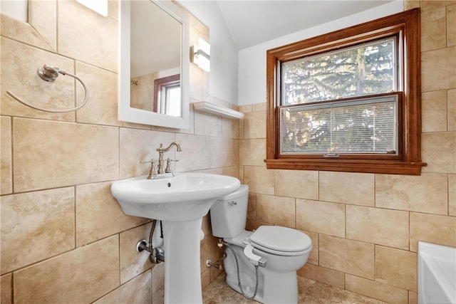 bathroom featuring a tub to relax in, tile walls, lofted ceiling, and toilet