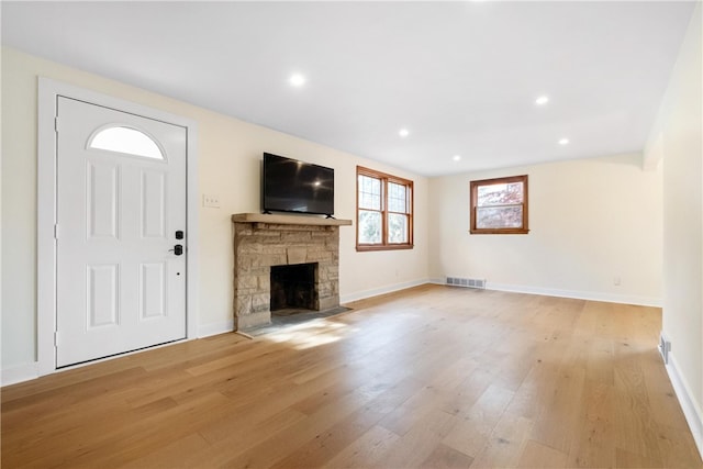 unfurnished living room featuring a stone fireplace and light hardwood / wood-style flooring