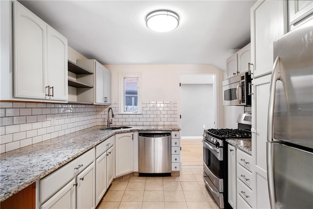 kitchen featuring white cabinets, tasteful backsplash, light tile patterned floors, sink, and stainless steel appliances