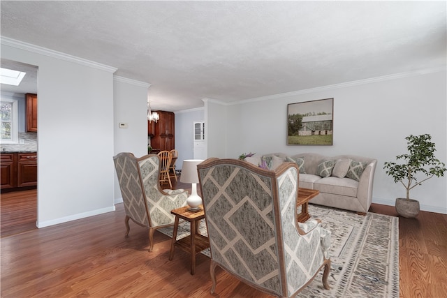 living room with ornamental molding, hardwood / wood-style floors, a textured ceiling, and an inviting chandelier