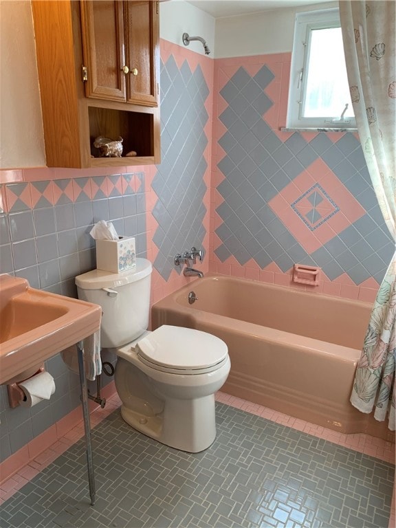 bathroom with tile walls, shower / tub combo, and toilet