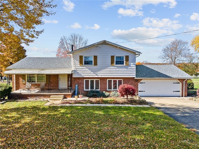 tri-level home with covered porch, a garage, and a front lawn