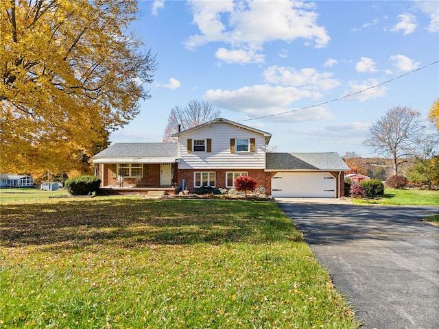 split level home featuring covered porch, a front yard, and a garage