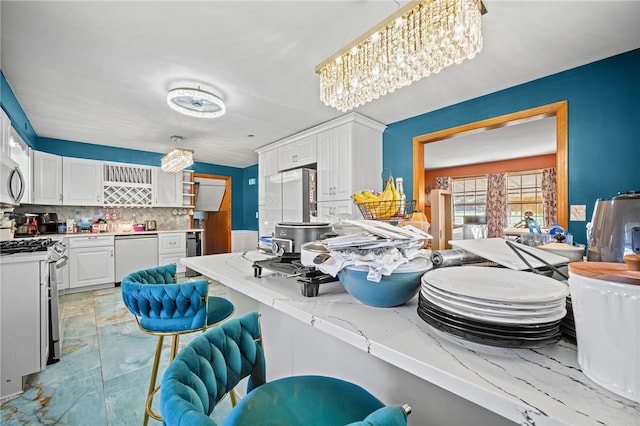 kitchen with appliances with stainless steel finishes, backsplash, kitchen peninsula, a kitchen breakfast bar, and white cabinetry