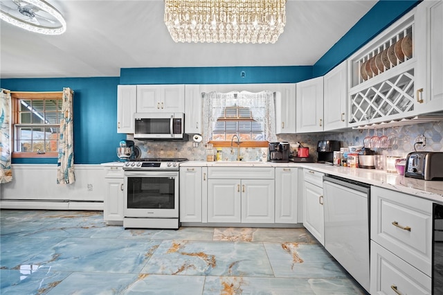 kitchen with backsplash, appliances with stainless steel finishes, white cabinetry, baseboard heating, and sink