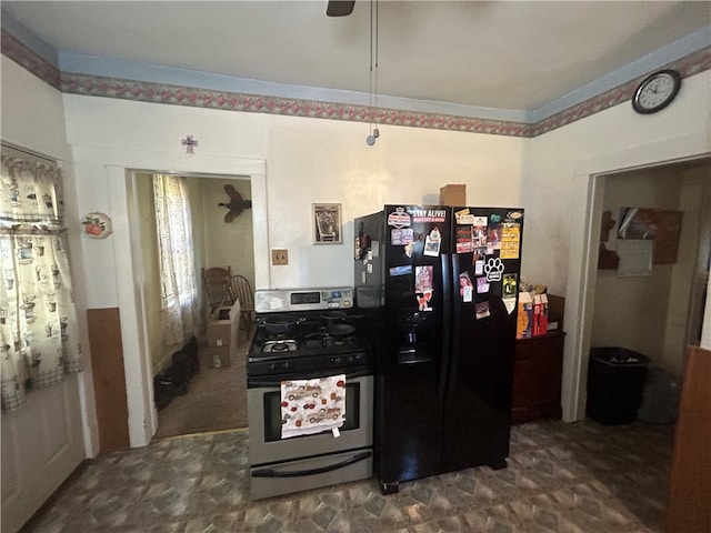 kitchen with stainless steel range with gas stovetop, dark carpet, and black fridge