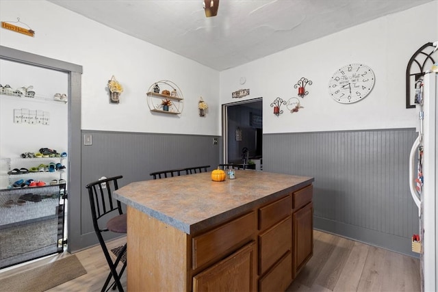 kitchen with refrigerator, a center island, a kitchen bar, and light hardwood / wood-style floors