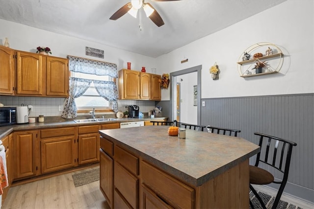 kitchen with a kitchen island, a breakfast bar area, backsplash, sink, and light wood-type flooring