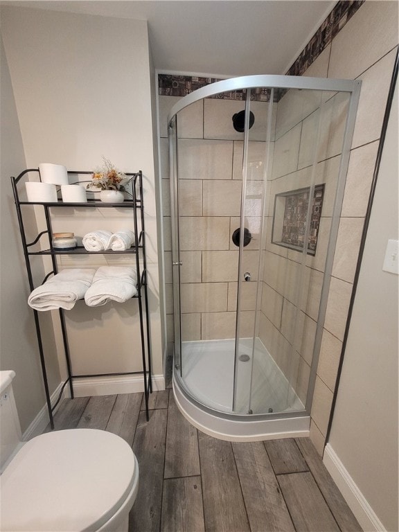 bathroom featuring a shower with door, hardwood / wood-style flooring, and toilet