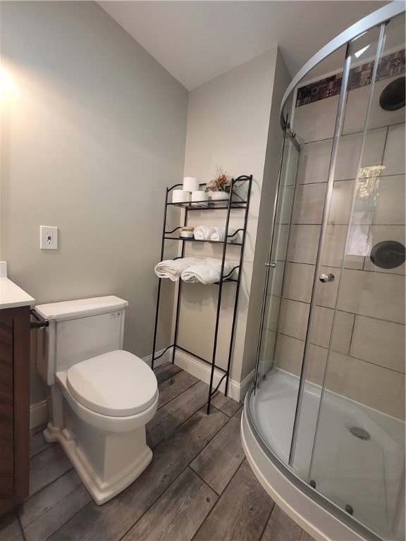 bathroom featuring vanity, a shower with shower door, hardwood / wood-style flooring, and toilet