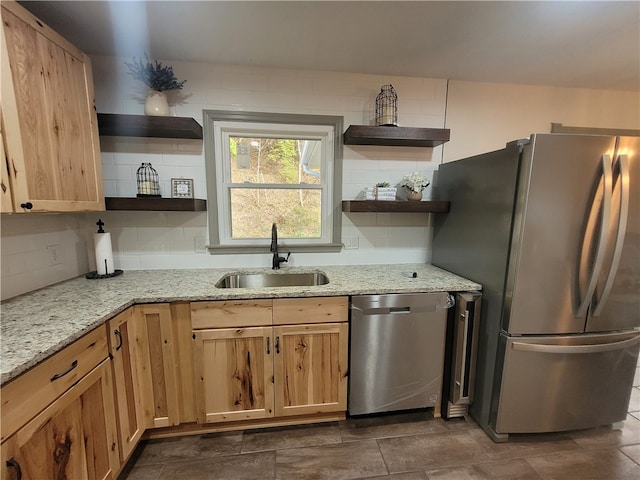 kitchen featuring light stone counters, appliances with stainless steel finishes, sink, and decorative backsplash