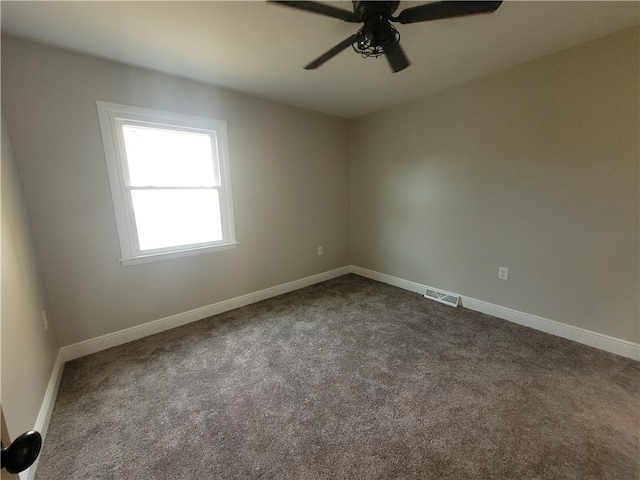 spare room with dark colored carpet and ceiling fan