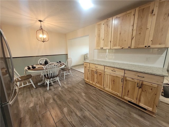 kitchen featuring decorative light fixtures, a notable chandelier, stainless steel refrigerator, light brown cabinets, and dark hardwood / wood-style floors