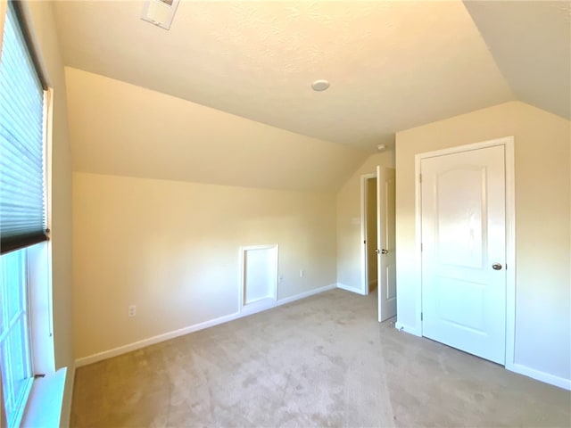 additional living space with vaulted ceiling and light colored carpet