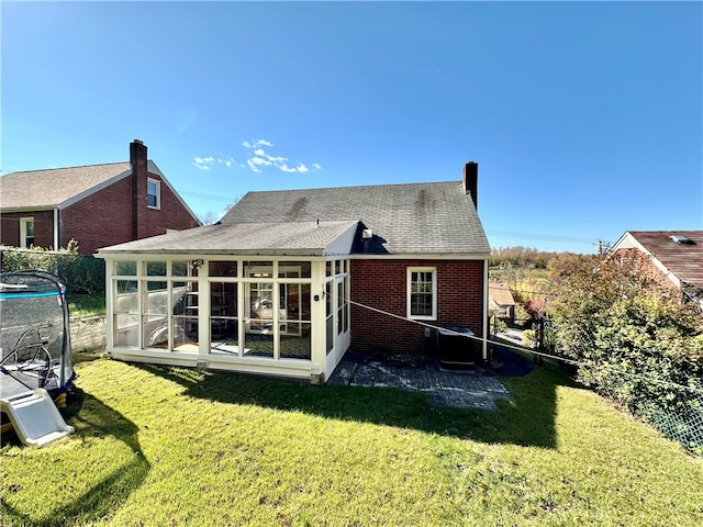 rear view of house with a sunroom and a lawn