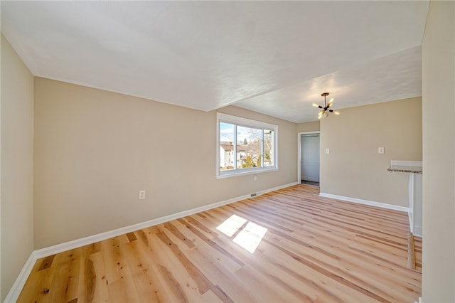 empty room with a chandelier and light wood-type flooring