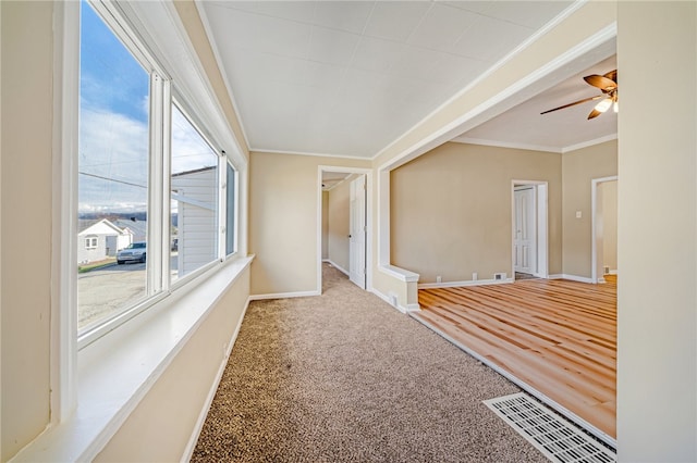 spare room with crown molding, carpet, a wealth of natural light, and ceiling fan