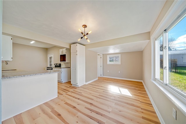 kitchen featuring an inviting chandelier, light hardwood / wood-style flooring, white cabinets, and light stone counters