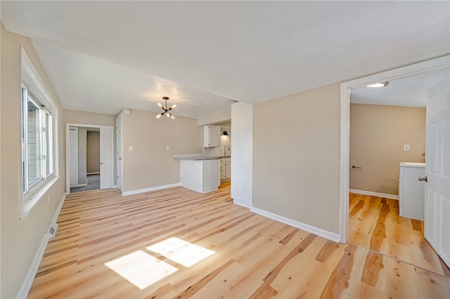 unfurnished living room with a notable chandelier and light wood-type flooring