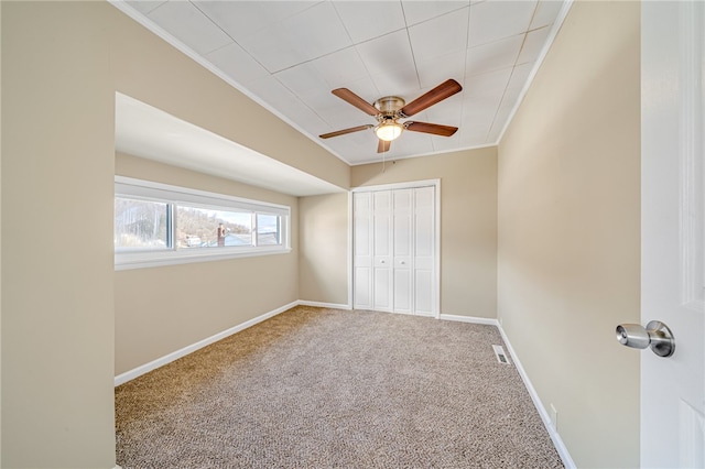 unfurnished bedroom with crown molding, carpet floors, a closet, and ceiling fan