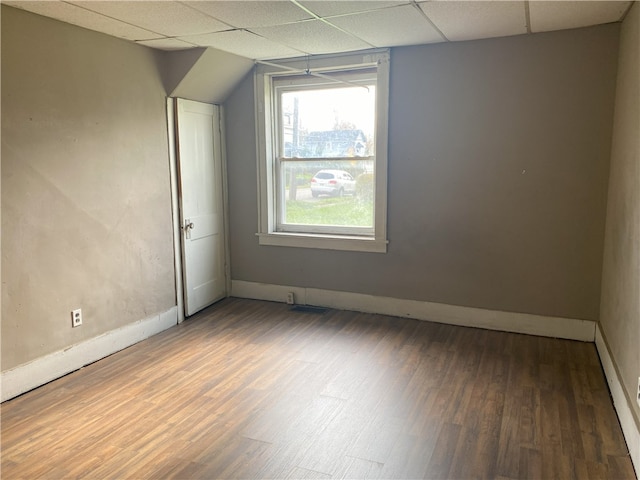 spare room with a drop ceiling and dark hardwood / wood-style flooring