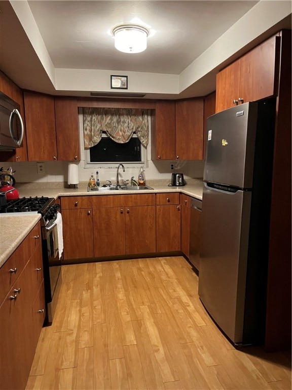 kitchen featuring stainless steel appliances, a raised ceiling, sink, and light wood-type flooring