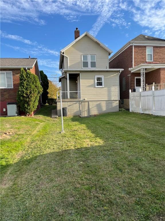 rear view of property with a lawn and central AC unit