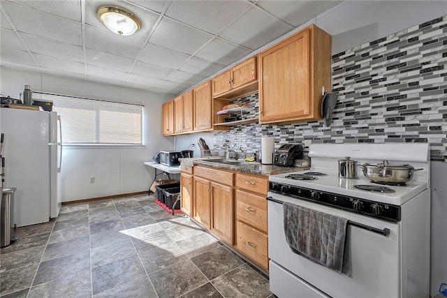 kitchen featuring a paneled ceiling, sink, backsplash, and white appliances