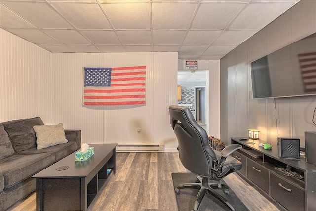 home office featuring hardwood / wood-style floors, baseboard heating, and a paneled ceiling