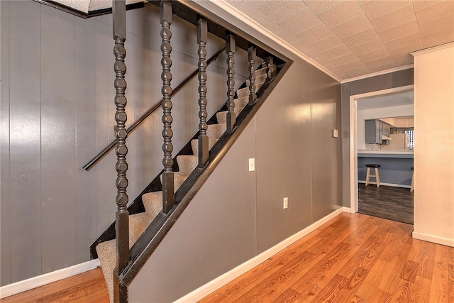 stairway featuring crown molding and hardwood / wood-style flooring