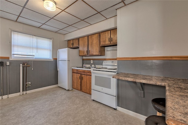 kitchen featuring light carpet, a paneled ceiling, and white appliances