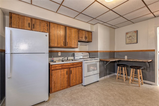 kitchen featuring sink, a drop ceiling, light colored carpet, and white appliances