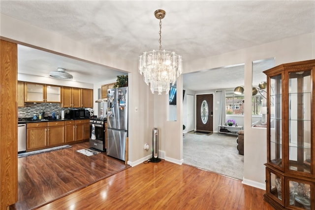 kitchen featuring tasteful backsplash, dark hardwood / wood-style flooring, pendant lighting, a notable chandelier, and stainless steel appliances