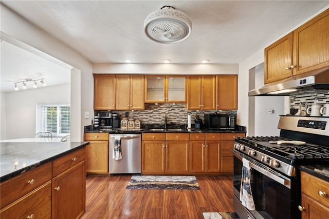 kitchen with decorative backsplash, dark hardwood / wood-style flooring, appliances with stainless steel finishes, vaulted ceiling, and sink