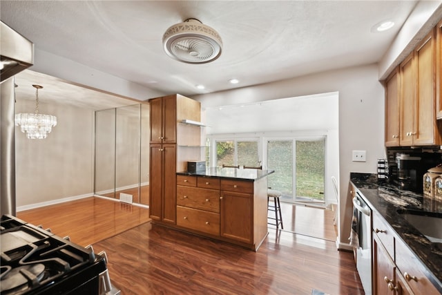 kitchen with kitchen peninsula, stove, dark wood-type flooring, and pendant lighting