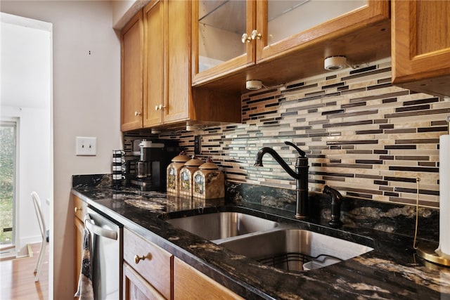 kitchen featuring tasteful backsplash, sink, dishwasher, light hardwood / wood-style floors, and dark stone counters