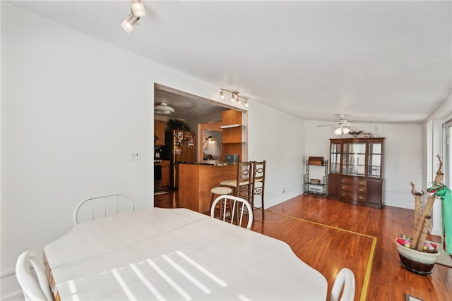 dining room featuring dark wood-type flooring, rail lighting, and ceiling fan