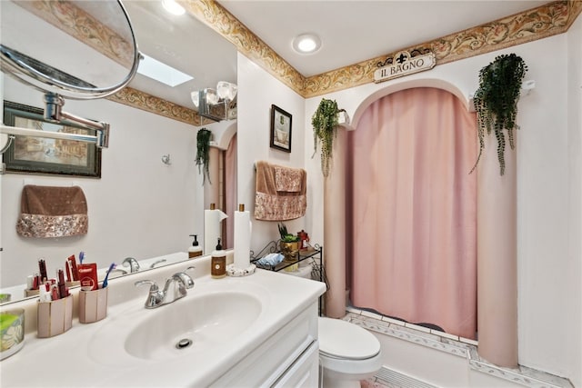 bathroom featuring vanity, a shower with curtain, toilet, and a skylight