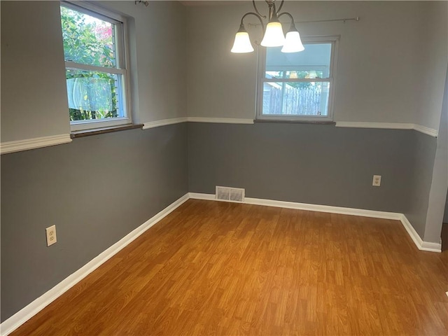 spare room featuring a chandelier and wood-type flooring