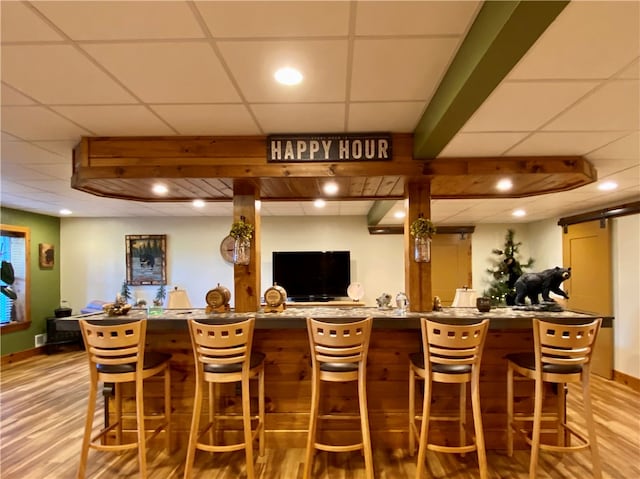 bar featuring a drop ceiling, light hardwood / wood-style flooring, and a barn door