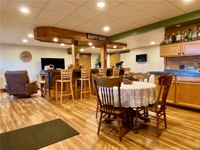 dining space featuring a paneled ceiling and light hardwood / wood-style flooring