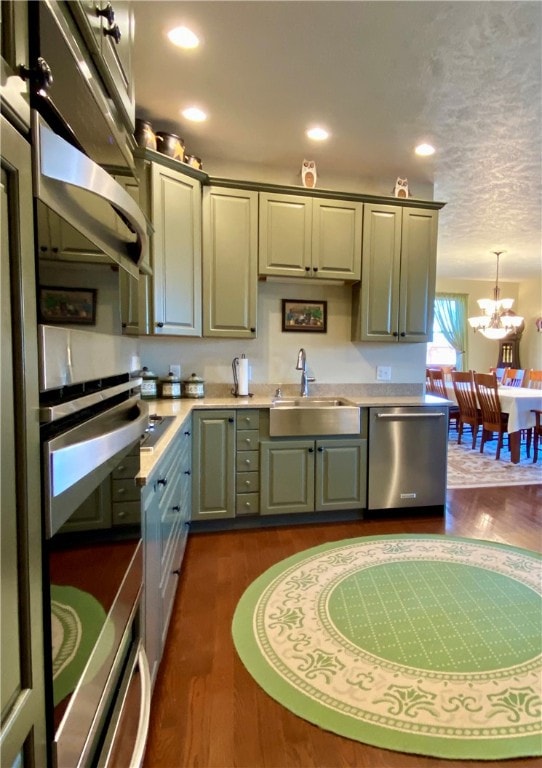 kitchen with sink, dark hardwood / wood-style flooring, stainless steel appliances, pendant lighting, and a notable chandelier