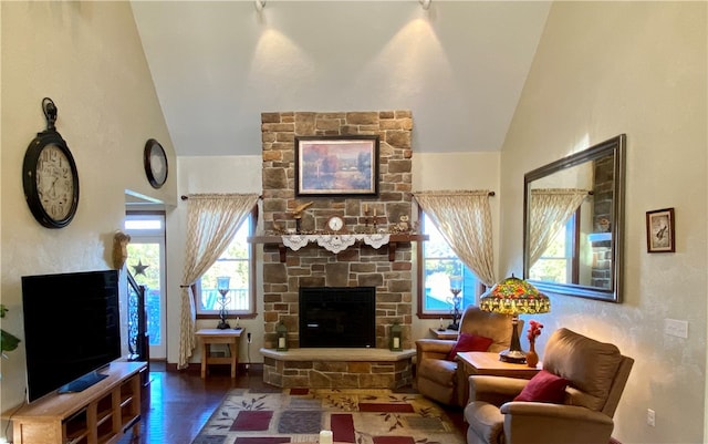 living room featuring hardwood / wood-style floors, vaulted ceiling, and a stone fireplace