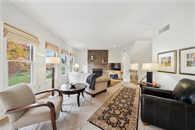 carpeted living room featuring a stone fireplace