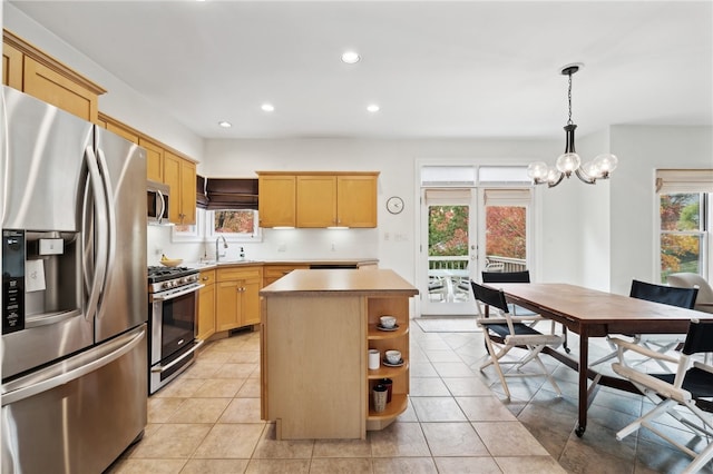 kitchen with pendant lighting, appliances with stainless steel finishes, a center island, and plenty of natural light