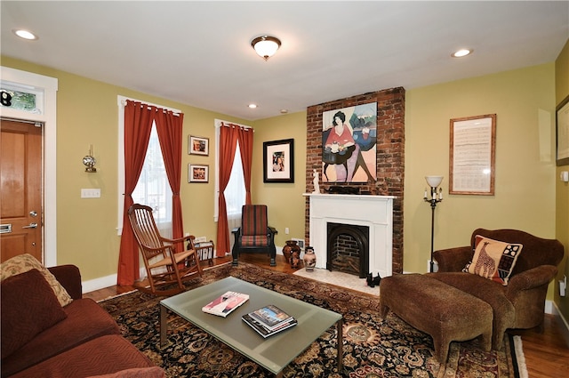 living room with wood-type flooring and a brick fireplace