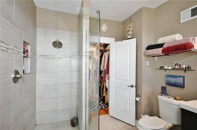 bathroom featuring vanity, tiled shower, toilet, and tile patterned floors