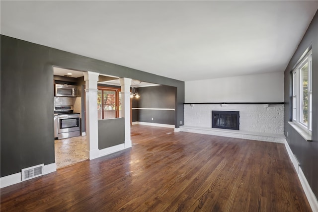 unfurnished living room featuring hardwood / wood-style flooring and decorative columns