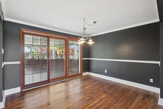 unfurnished dining area featuring dark wood-type flooring, ornamental molding, and an inviting chandelier